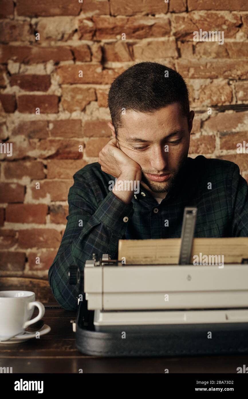 buon giovane scrittore che lavora su una macchina da scrivere classica, è felice e senza fretta Foto Stock