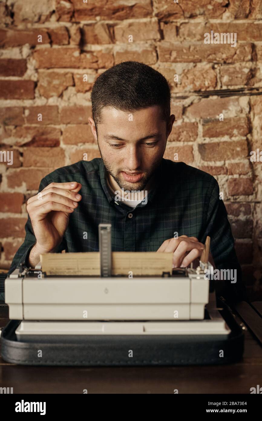 buon giovane scrittore che lavora su una macchina da scrivere classica, è felice e senza fretta Foto Stock