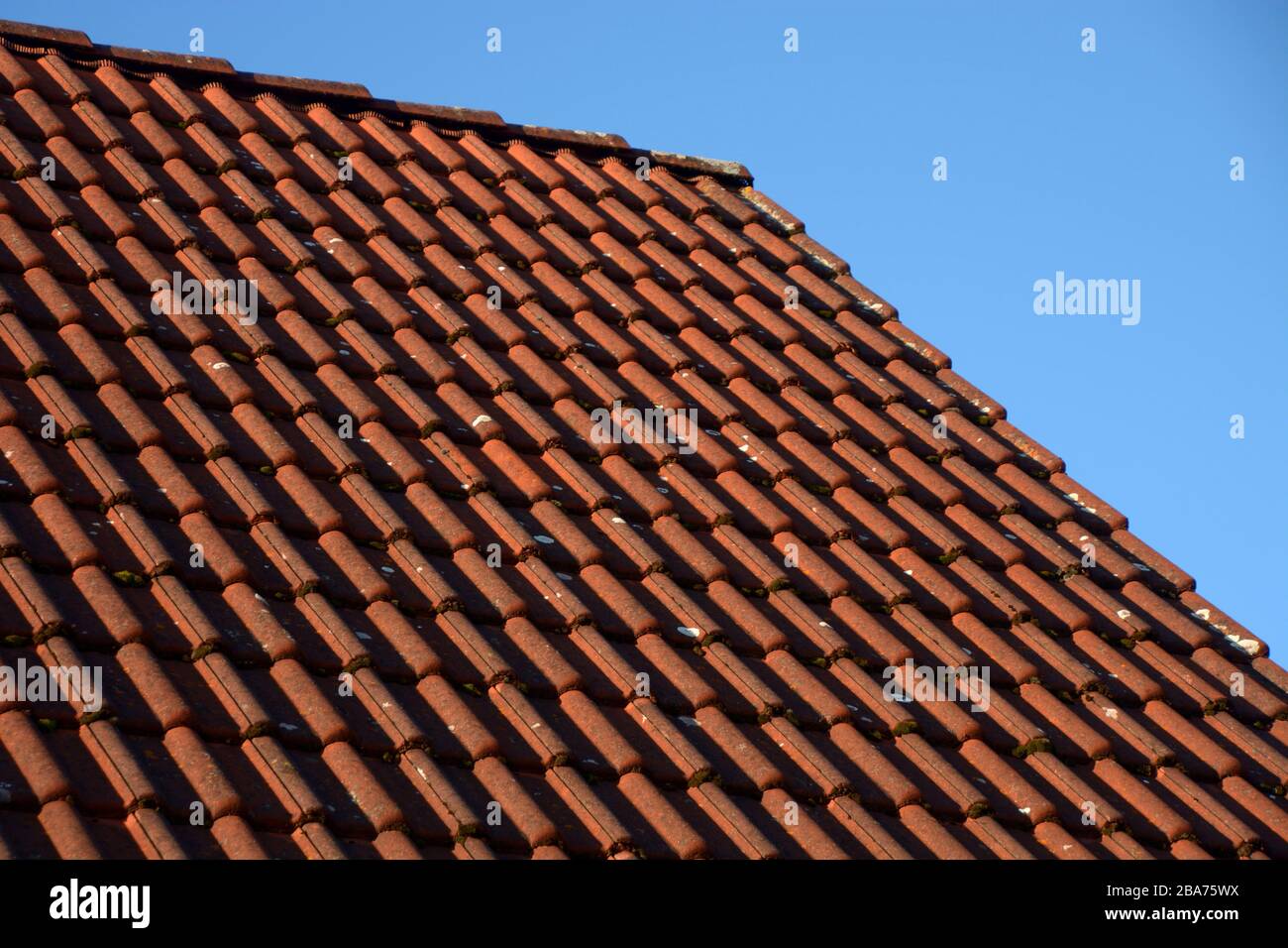 tetto sporco illuminato dal sole, vecchio tetto rosso piastrelle sporche di fronte al cielo blu Foto Stock