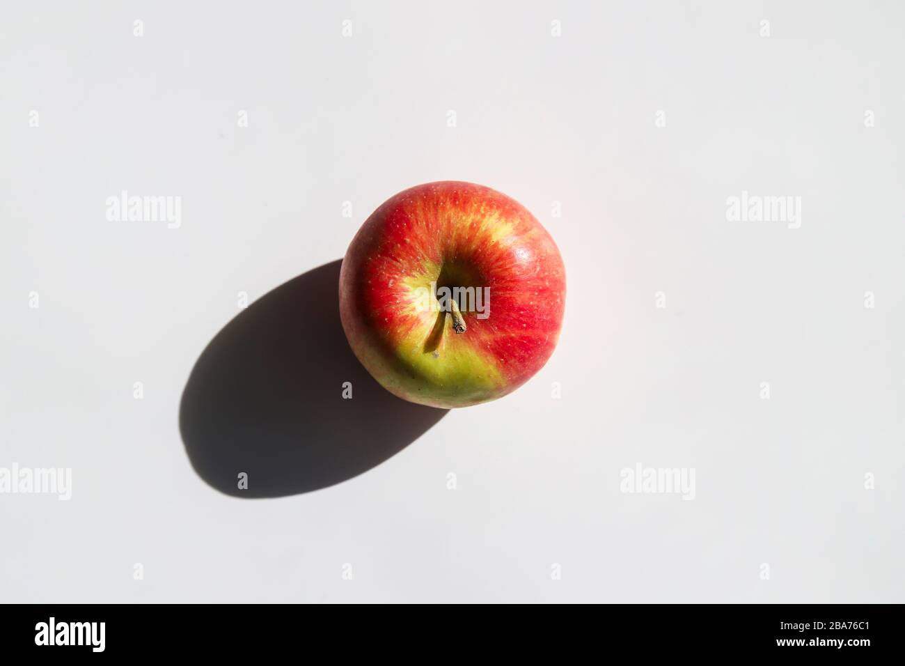 Mela fresca con forte ombra su sfondo bianco al giorno di sole. Concetto di cibo minimale alla moda. Frutta naturale biologica Foto Stock