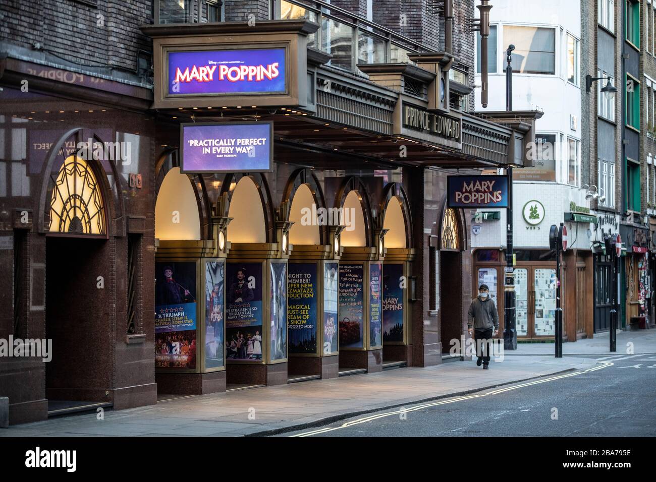 Un uomo che indossa una maschera protettiva passa davanti al Prince Edward Theatre su una strada vuota mentre ristoranti e teatri rimangono chiusi in Old Compton Street, nel cuore del Soho di Londra durante il Coronavirus Lockdown. Gli economisti del Regno Unito prevedono che un crollo potrebbe costare più vita di Covid-19 Credit: Jeff Gilbert/Alamy Live News Foto Stock