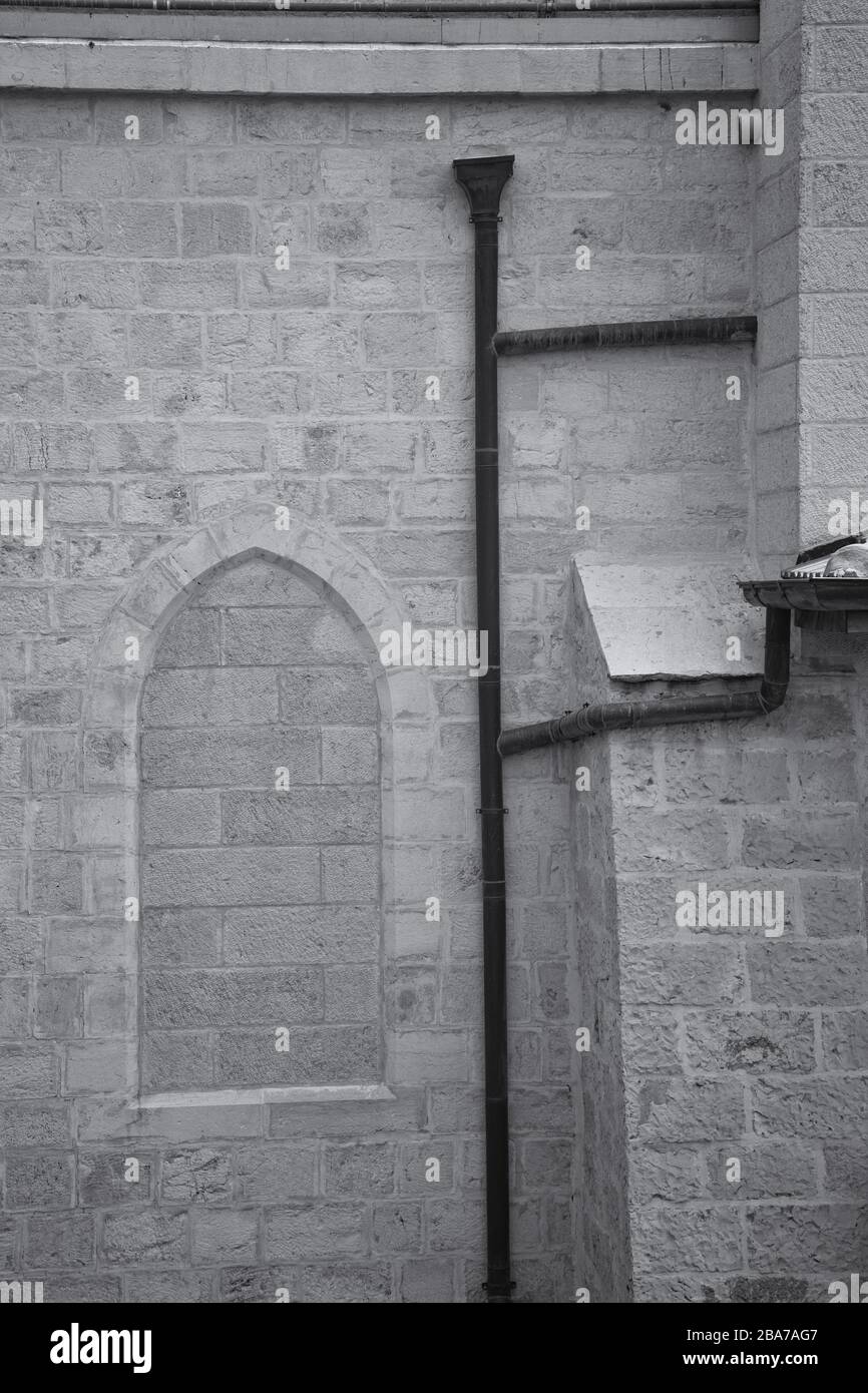 Immagine verticale in scala di grigi di una pipa piovana sul lato di un edificio a Gerusalemme, Israele. Foto Stock