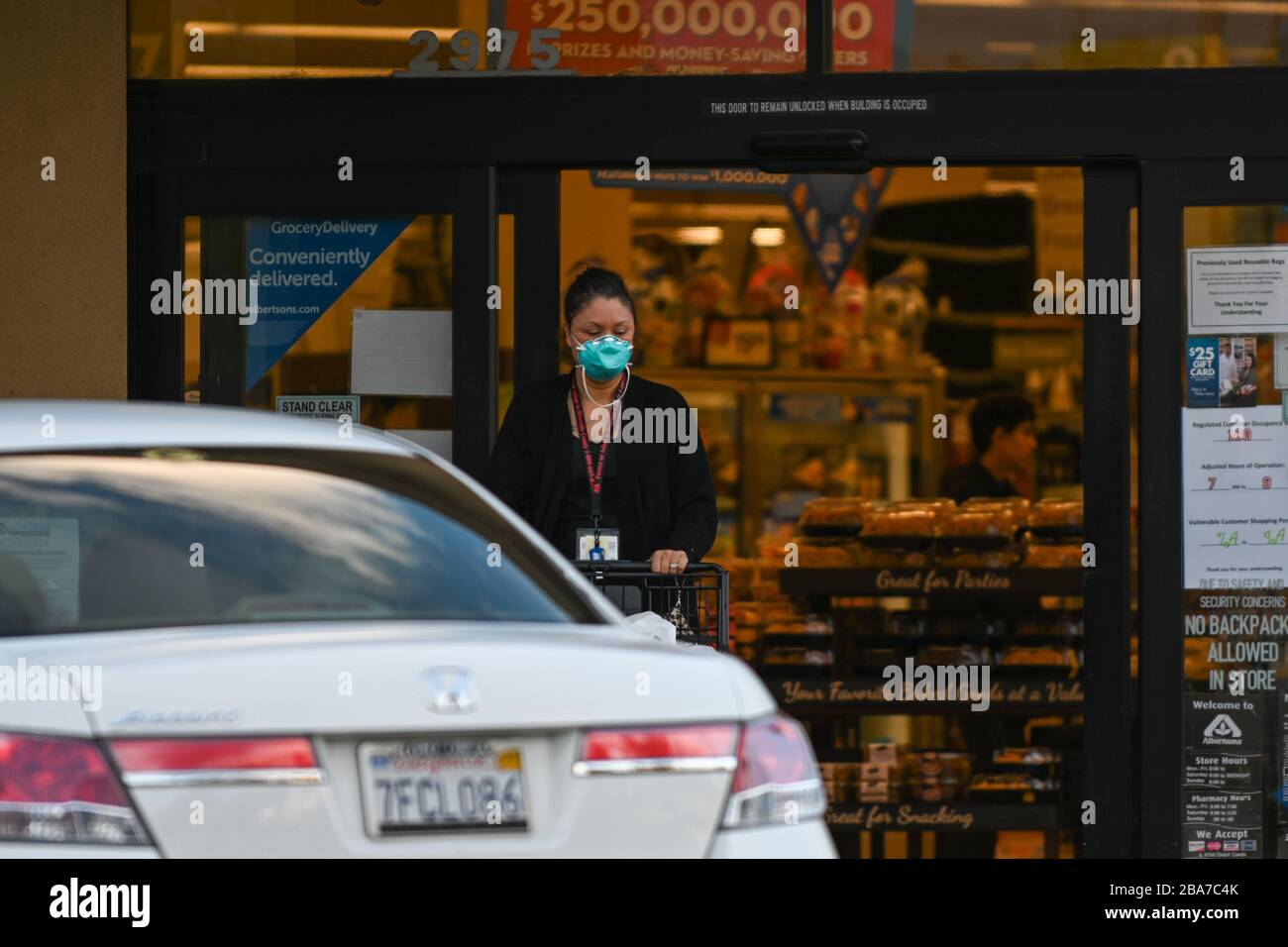 Una donna esce da un negozio di alimentari Albertsons mentre indossa una maschera il, Mercoledì, 25 marzo 2020, a Riverside, California. La catena di negozi di alimentari ha annunciato Lunedi che stanno assumendo più persone e la retribuzione crescente per aiutare a servire i bisogni durante il romanzo coronavirus pandemic. (Dylan Stewart/immagine dello sport) (Foto di IOS/Espa-Images) Foto Stock