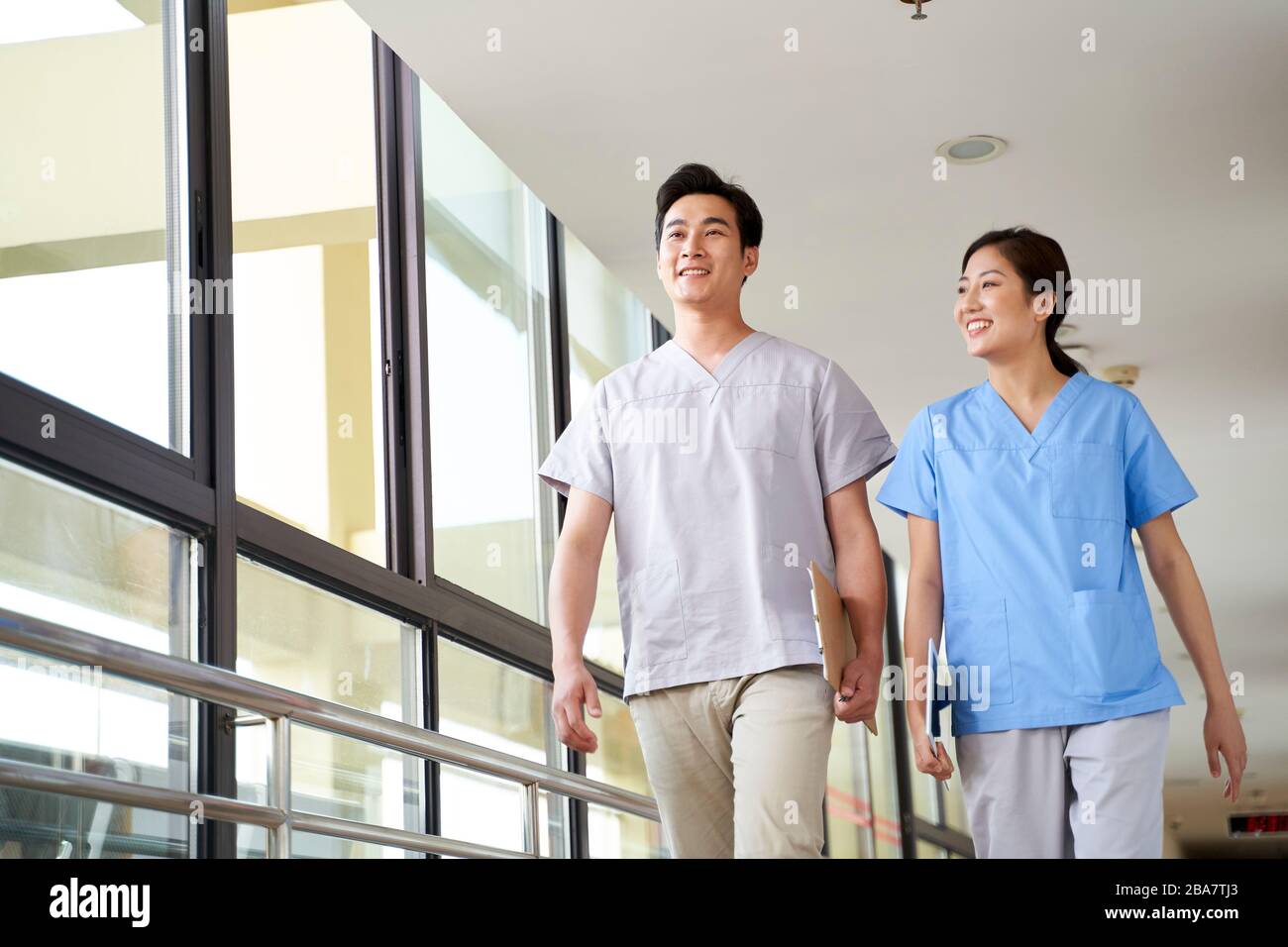 felici giovani terapisti asiatici a piedi parlare in corridoio di casa di cura Foto Stock