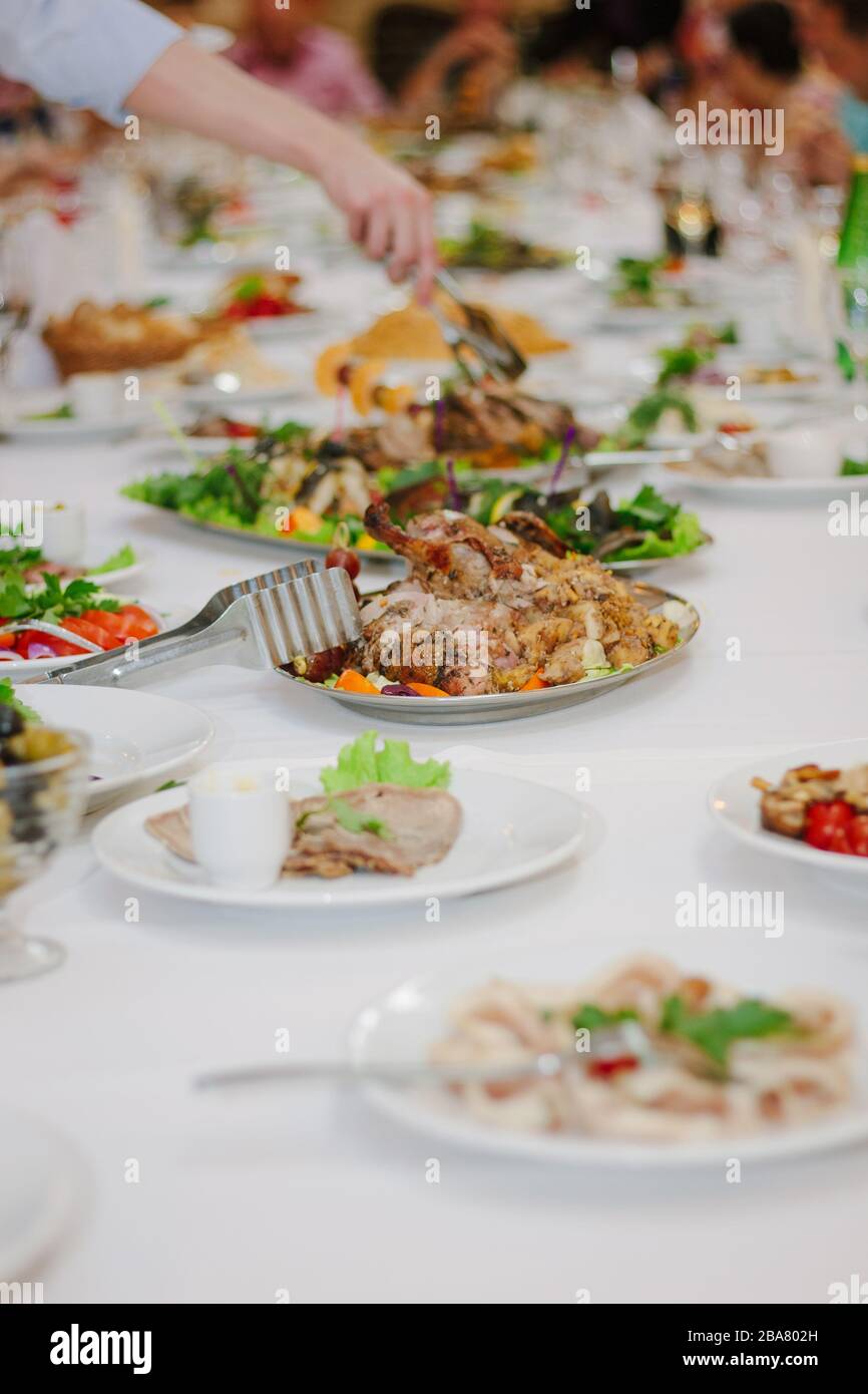 Tavolo da pranzo - mano con le tenaglie che prendono un alimento Foto Stock