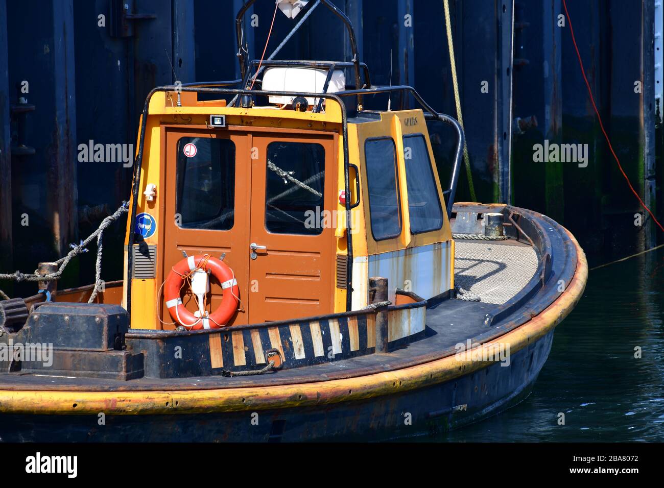 Piccola barca a rimorchiatore ormeggiata nel porto contro la struttura in acciaio di una banchina a Rotterdam Foto Stock