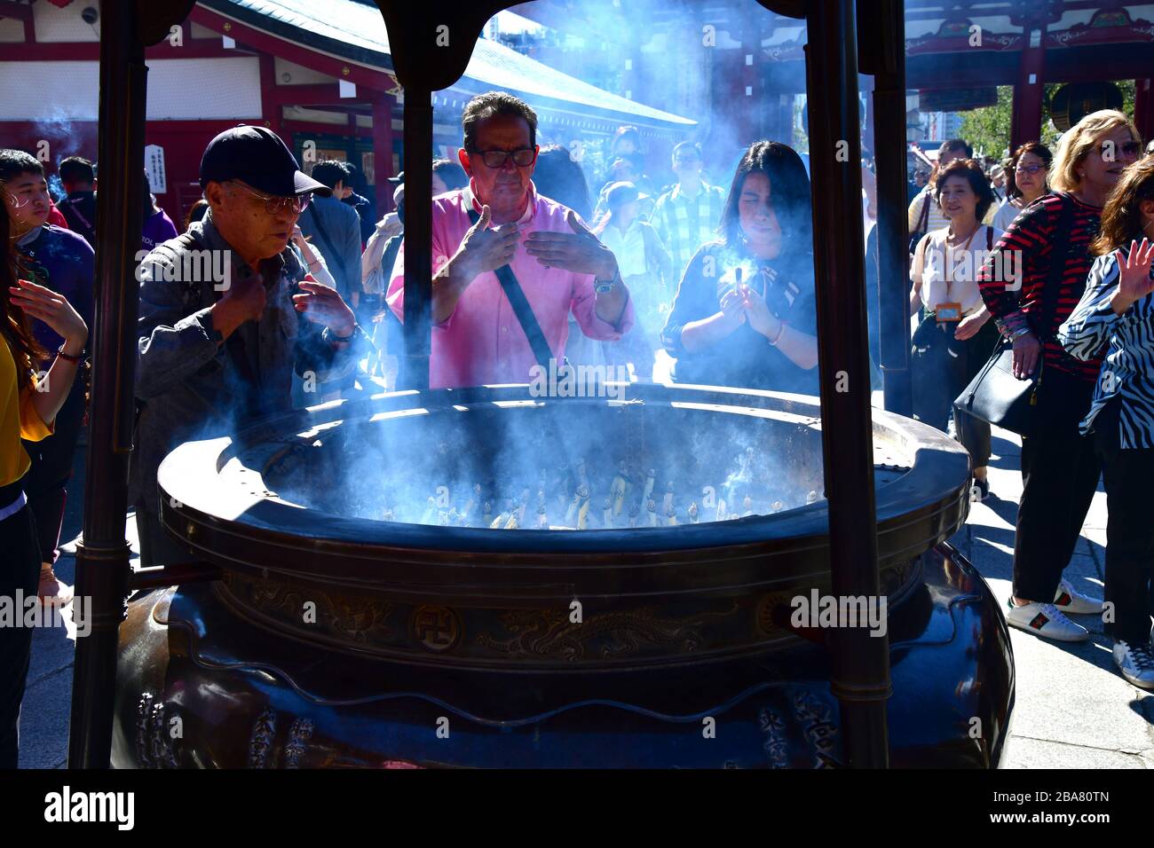 Persone intorno al bruciatore di incenso al tempio di Sensoji ad Asakusa, Tokyo. Credere è il fumo dal bruciatore di incenso ha un effetto healing. Foto Stock