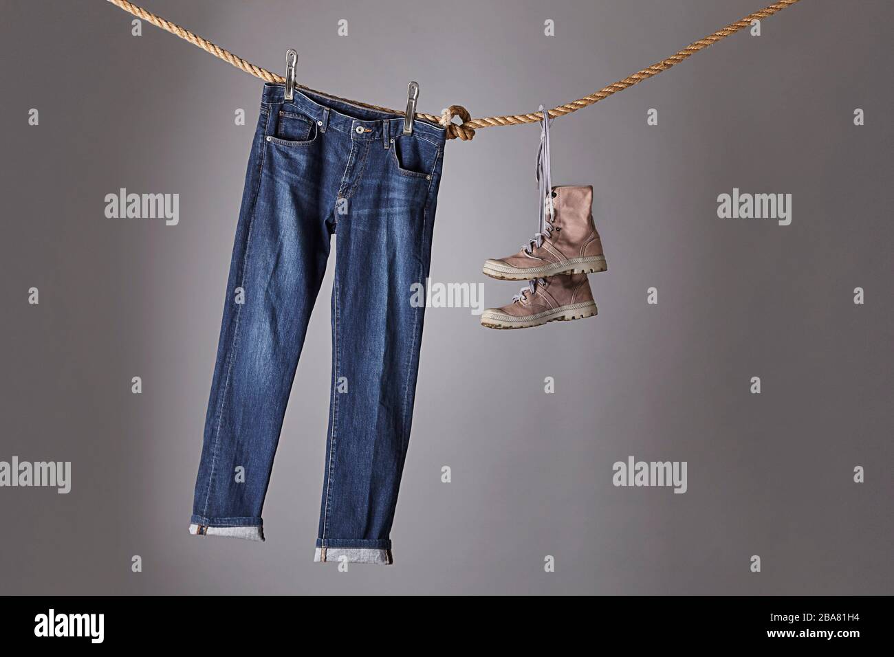 Un jeans blu appeso su una corda, fianco a fianco con stivali Foto Stock