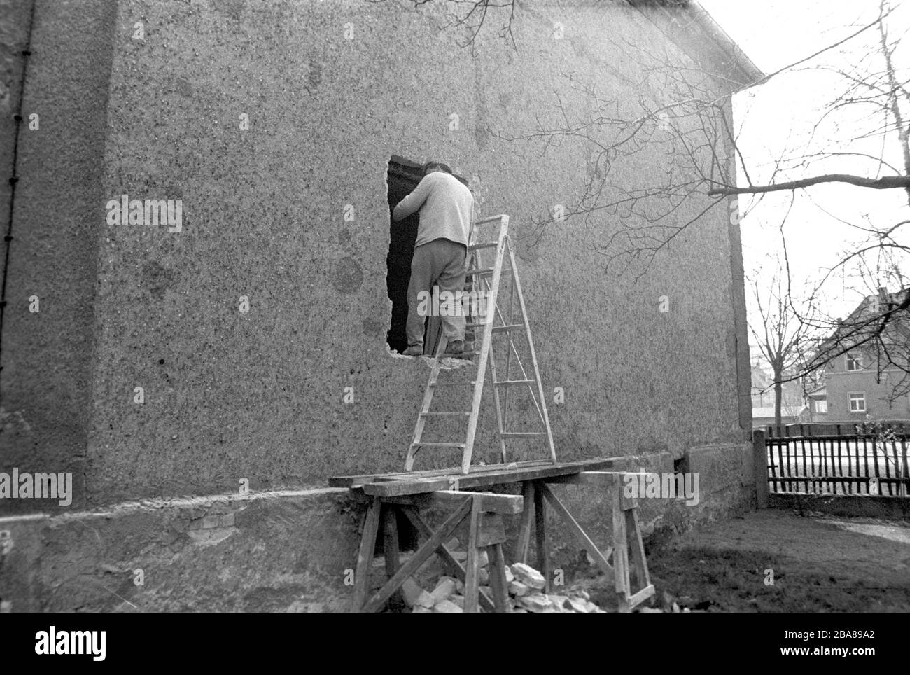 30 novembre 1976, Sassonia, Lipsia: In una vecchia casa degli anni '20 a Lipsia, un artigiano rompe un foro nel muro per inserire le finestre. Data esatta dello shot non nota. Foto: Volkmar Heinz/dpa-Zentralbild/ZB Foto Stock