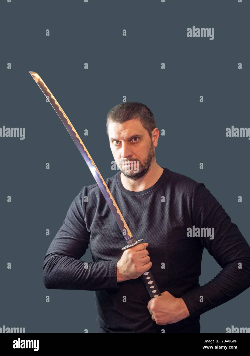 L'uomo di poppa con spada lunga in vestiti neri su sfondo scuro Foto stock  - Alamy