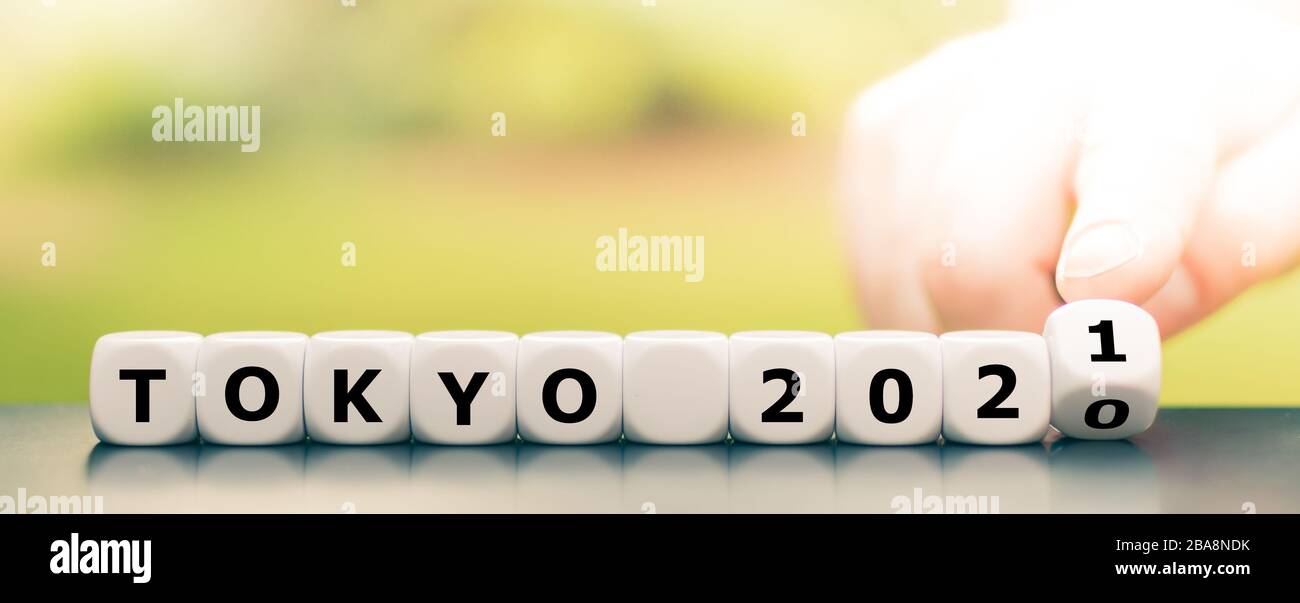La mano gira i dadi e cambia l'espressione "Tokyo 2020" in "Tokyo 2021". Foto Stock
