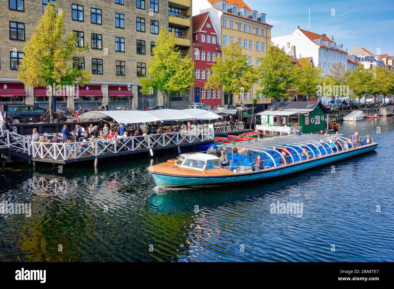 Christianshavn Canal a Copenaghen in Danimarca con ristorante & vasi lungo entrambe le banchine del porto e la nave da crociera passando attraverso Foto Stock