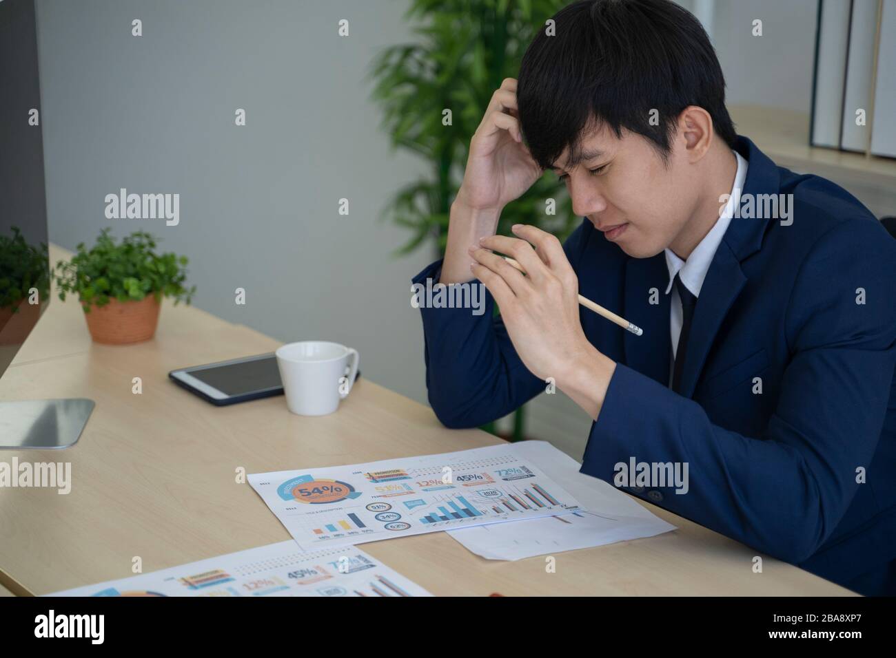 Uomo d'affari asiatico che ha problemi in ufficio. Foto Stock
