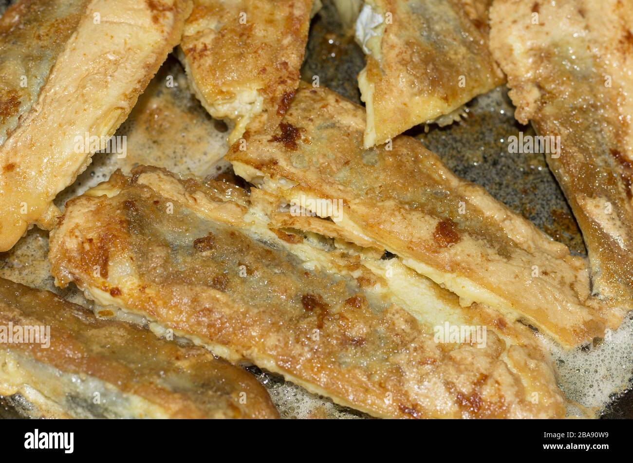 Pezzi di Whiting fritto in pastella in padella con olio vegetale Foto Stock