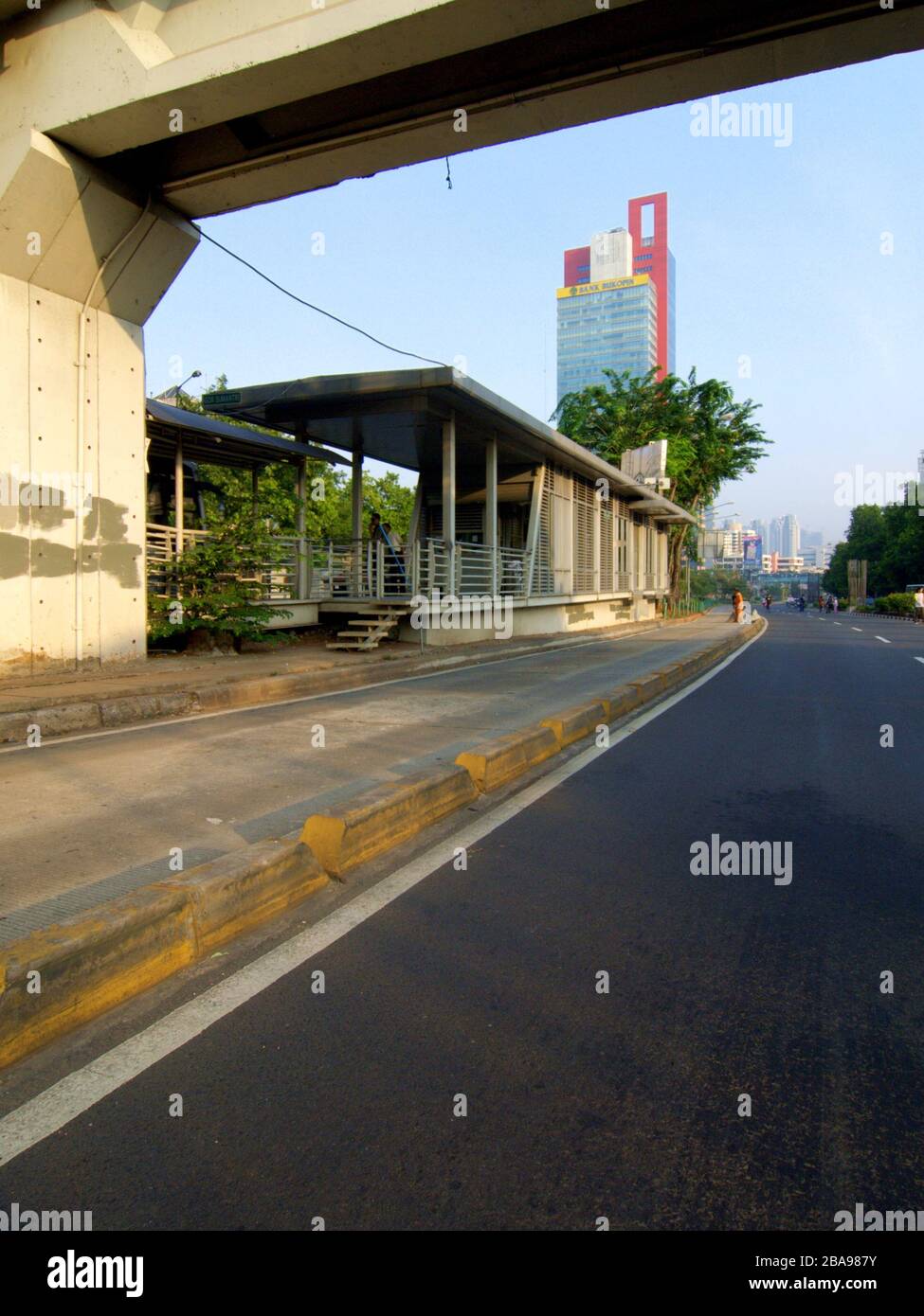 Una strada vuota, un cartello pubblicitario e una stazione della piattaforma di autobus accanto ad un ponte a Giacarta, Indonesia. Foto Stock