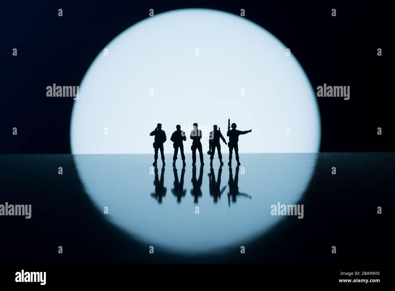Blocchi stradali forze di polizia o esercito contro bianco cerchio rotondo luce concetto immagini - basso chiave miniatura figure giocattolo delle forze di sicurezza - silhouette di ar Foto Stock