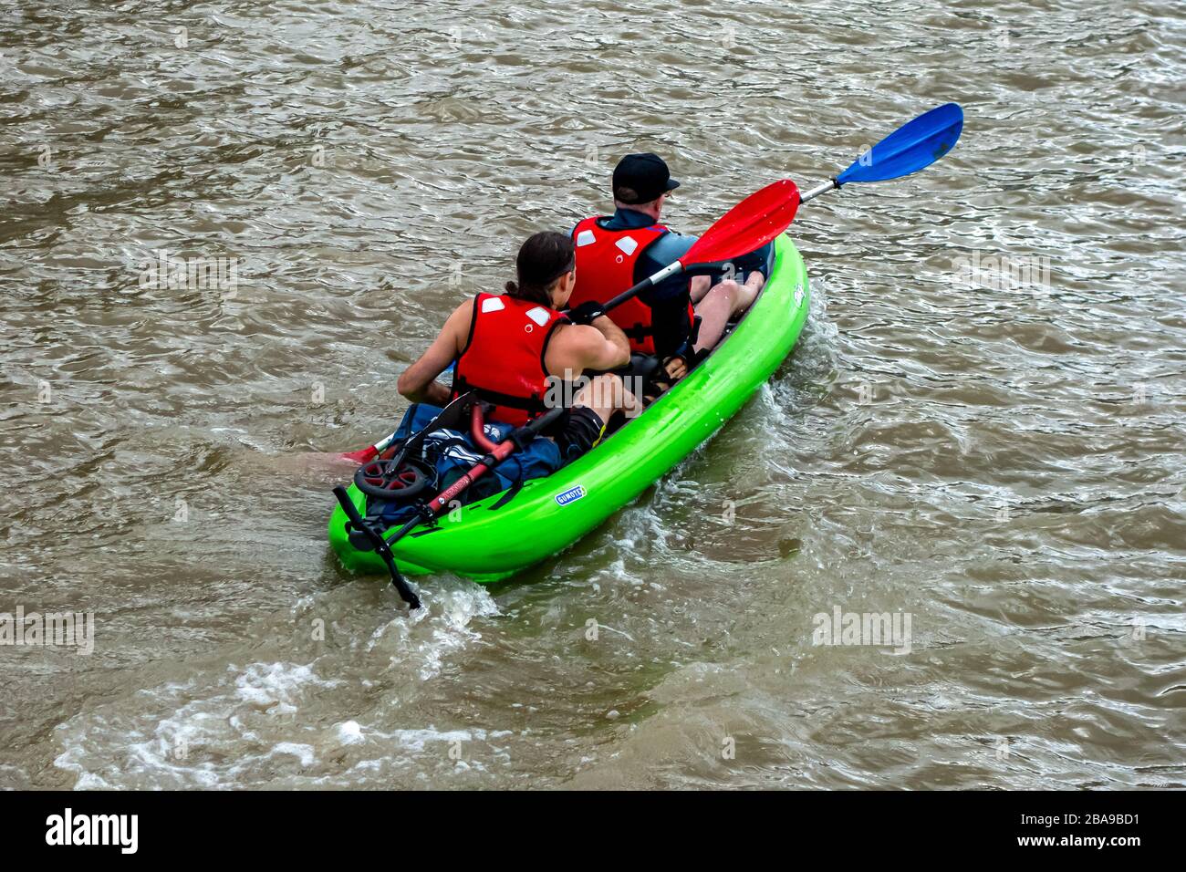 Vista posteriore di due uomini su una canoa verde brillante, viaggiando lungo il Tamigi vicino alla Greenwich Peninsula London, preso il 18th agosto 2019 Foto Stock