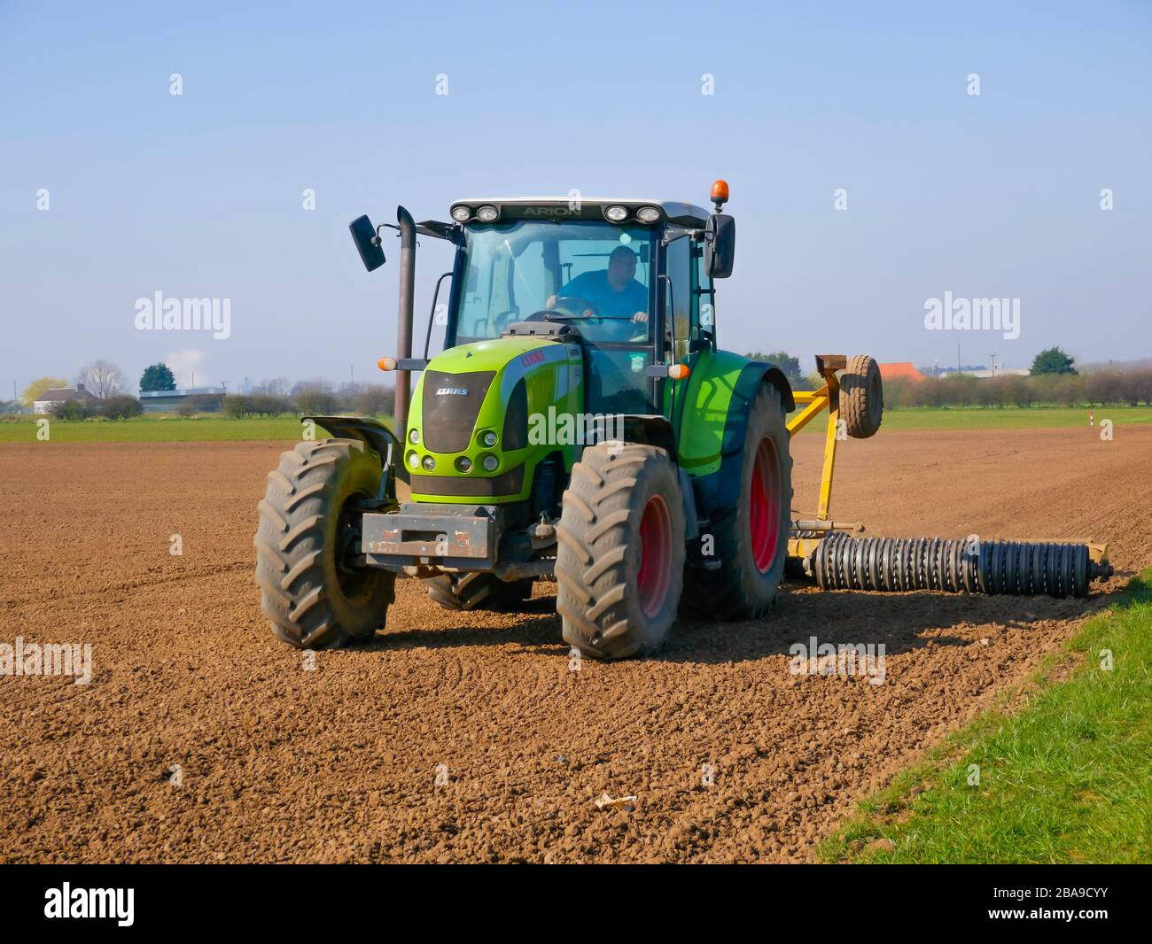 Un trattore e un erpice che preparano un campo per la semina in primavera nel North Yorkshire Inghilterra Regno Unito Foto Stock