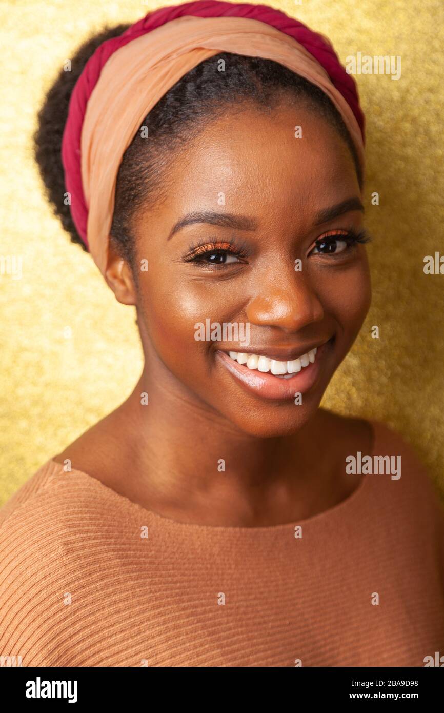 Ritratto di una giovane donna nera che indossa un archetto e guarda la fotocamera. Foto Stock