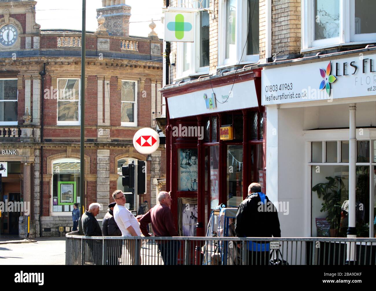 Paignton, Devon, Inghilterra: I clienti osservano la regola di distanza sociale di 6,5ft mentre accodano fuori di una farmacia durante il blocco del coronavirus Foto Stock