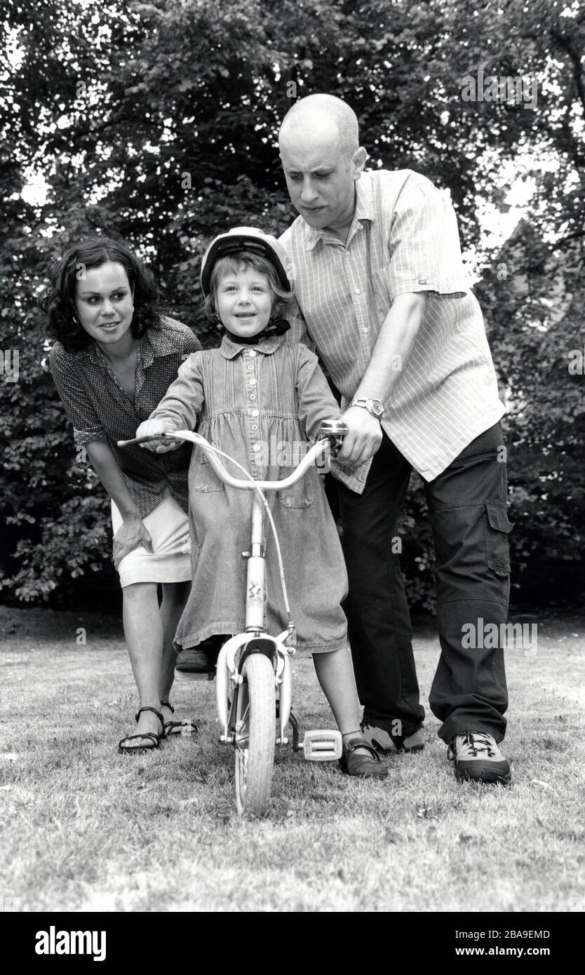 I genitori con la loro figlia imparano a guidare una bicicletta nel Regno Unito anni '90 Foto Stock