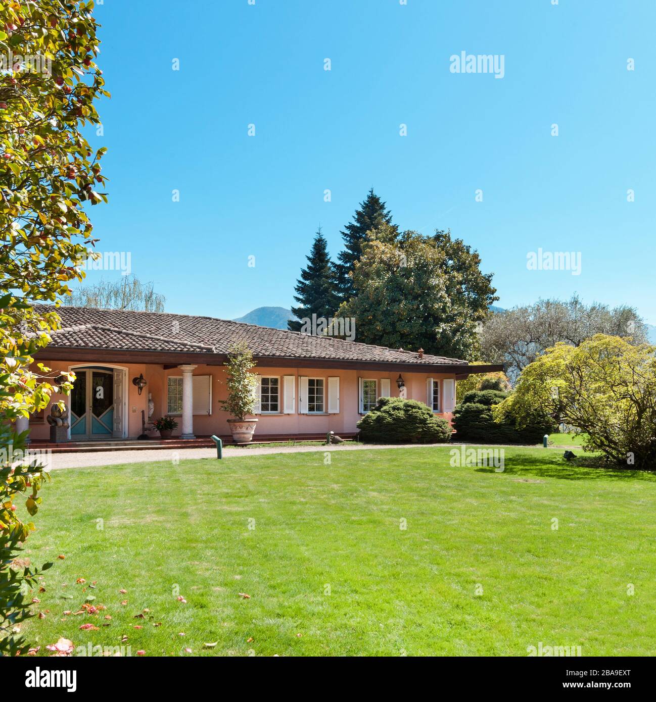 Prato verde e bella casa in una soleggiata giornata di primavera Foto Stock