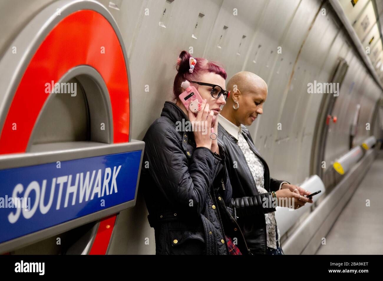 Un uomo effettua una telefonata sulla piattaforma della stazione metropolitana di Southwark, parte del sistema della metropolitana di Londra Foto Stock