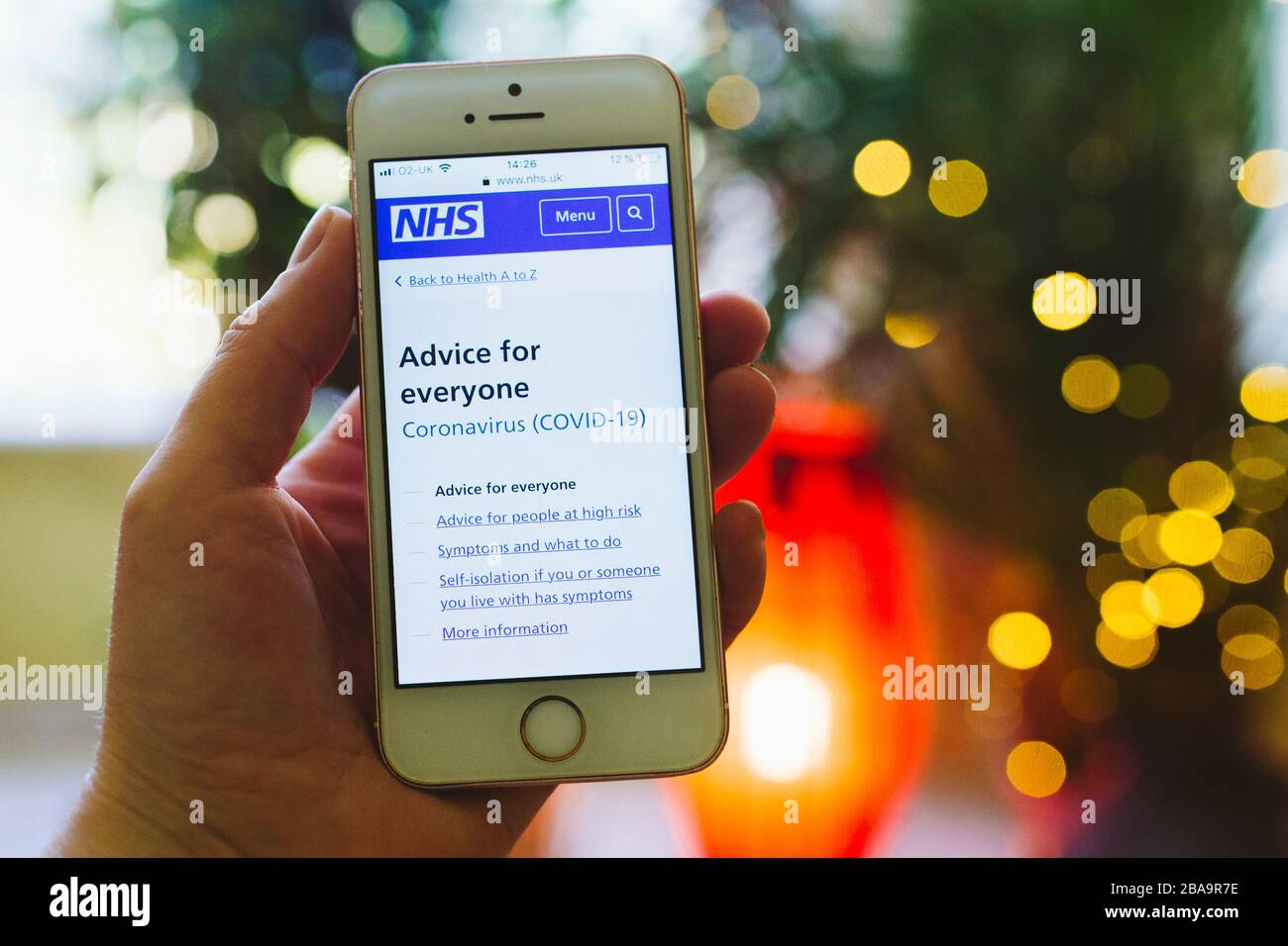 Persona che tiene il telefono cellulare con NHS Coronavirus Covid19 consigli sullo schermo Foto Stock