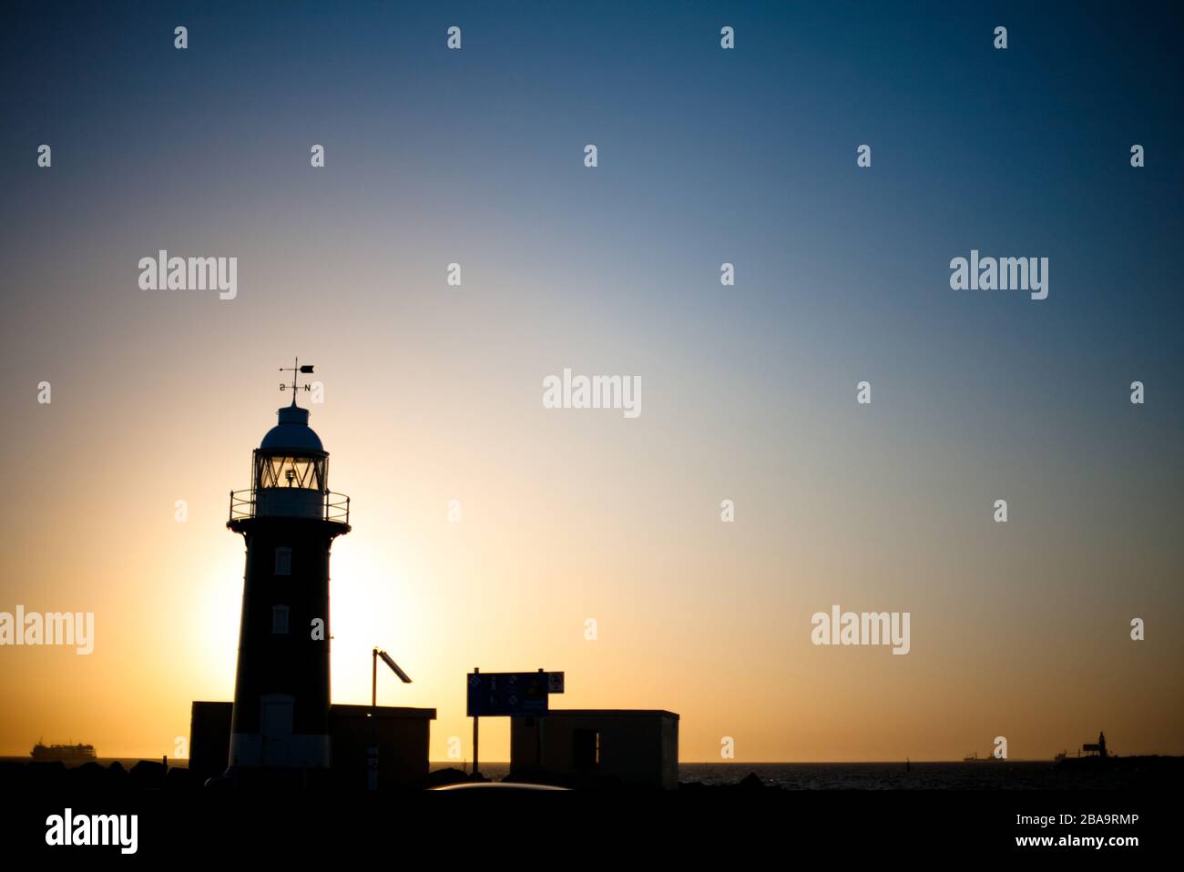 Il verde dipinto South Mole Lighthouse, nella baia di Fremantle, Australia Occidentale al tramonto Foto Stock
