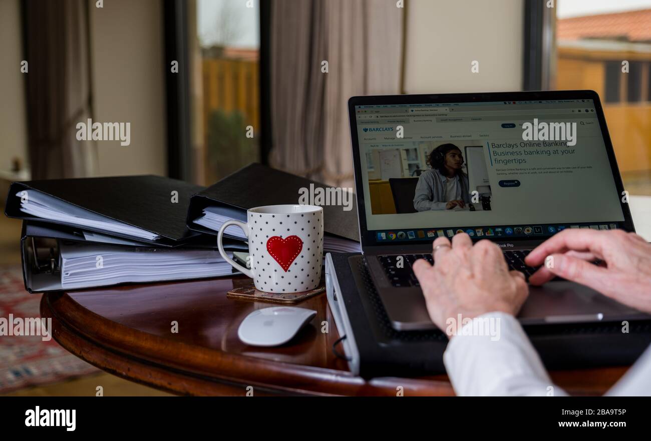 Donna che lavora su un laptop sul tavolo a casa con schermo che mostra il sito web di Barclays online banking Foto Stock