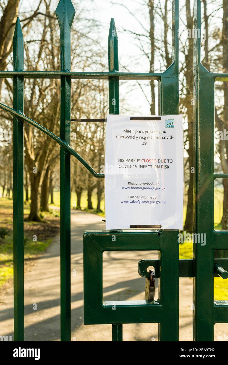 Un parco vuoto dietro porte chiuse in una giornata di sole durante le crisi di coronavirus. Una notifica del consiglio vale of Glamorgan in gallese e inglese è allegata. Foto Stock