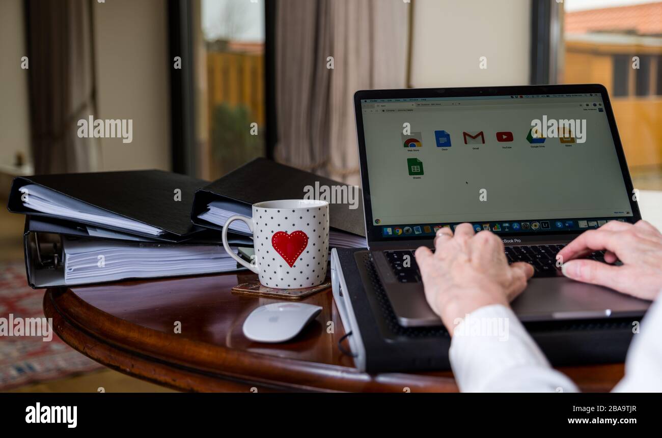 Donna che lavora su un computer portatile sul tavolo a casa con schermo che mostra le applicazioni Google Foto Stock