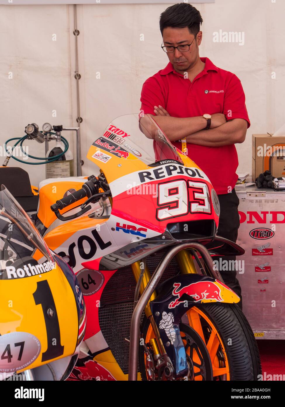 Un uomo giapponese che si trova accanto a una moto da corsa Repsol Honda, al Goodwood Festival of Speed, West Sussex UK Foto Stock