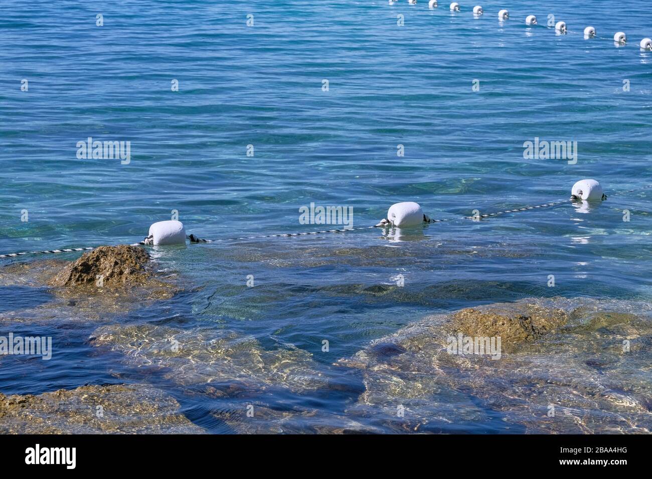 Il galleggiante tiene il cavo in acqua blu, in primo piano. Boa bianca in plastica nel mare blu. Paesaggio di mare in estate. Foto Stock
