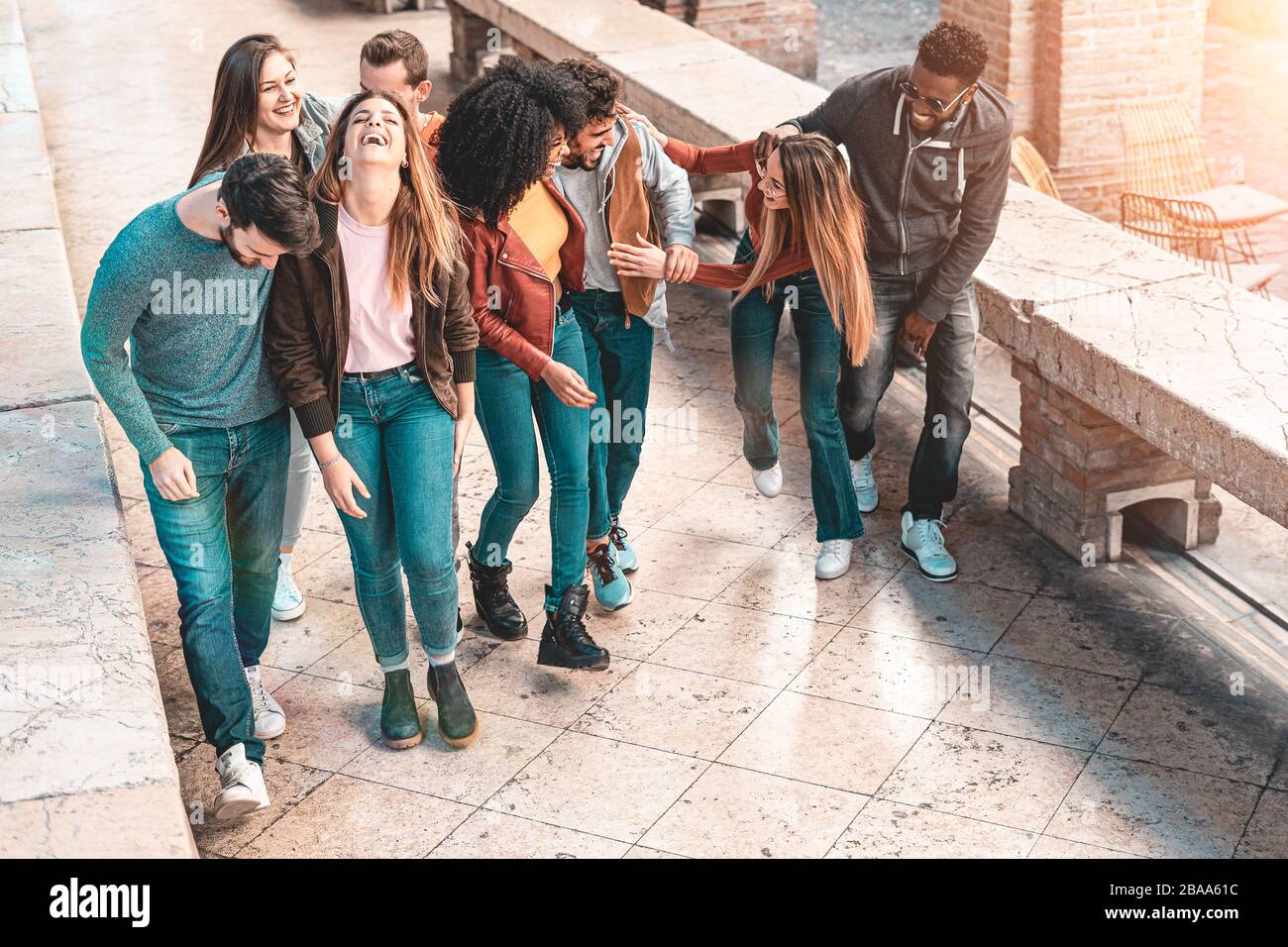 Gruppo misto di giovani che sorride e hanno camminato insieme e chiacchierato all'aperto per strada. Concetto di stile di vita per ragazzi e ragazze. Teal e o Foto Stock