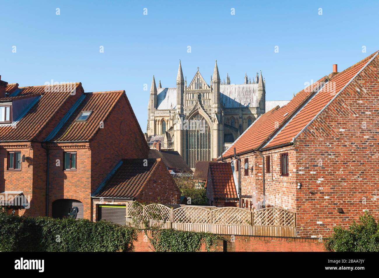 Vista dell'antico minster attraverso le moderne case cittadine in una bella mattina primaverile sotto il cielo blu a Beverley, Yorkshire, Regno Unito. Foto Stock