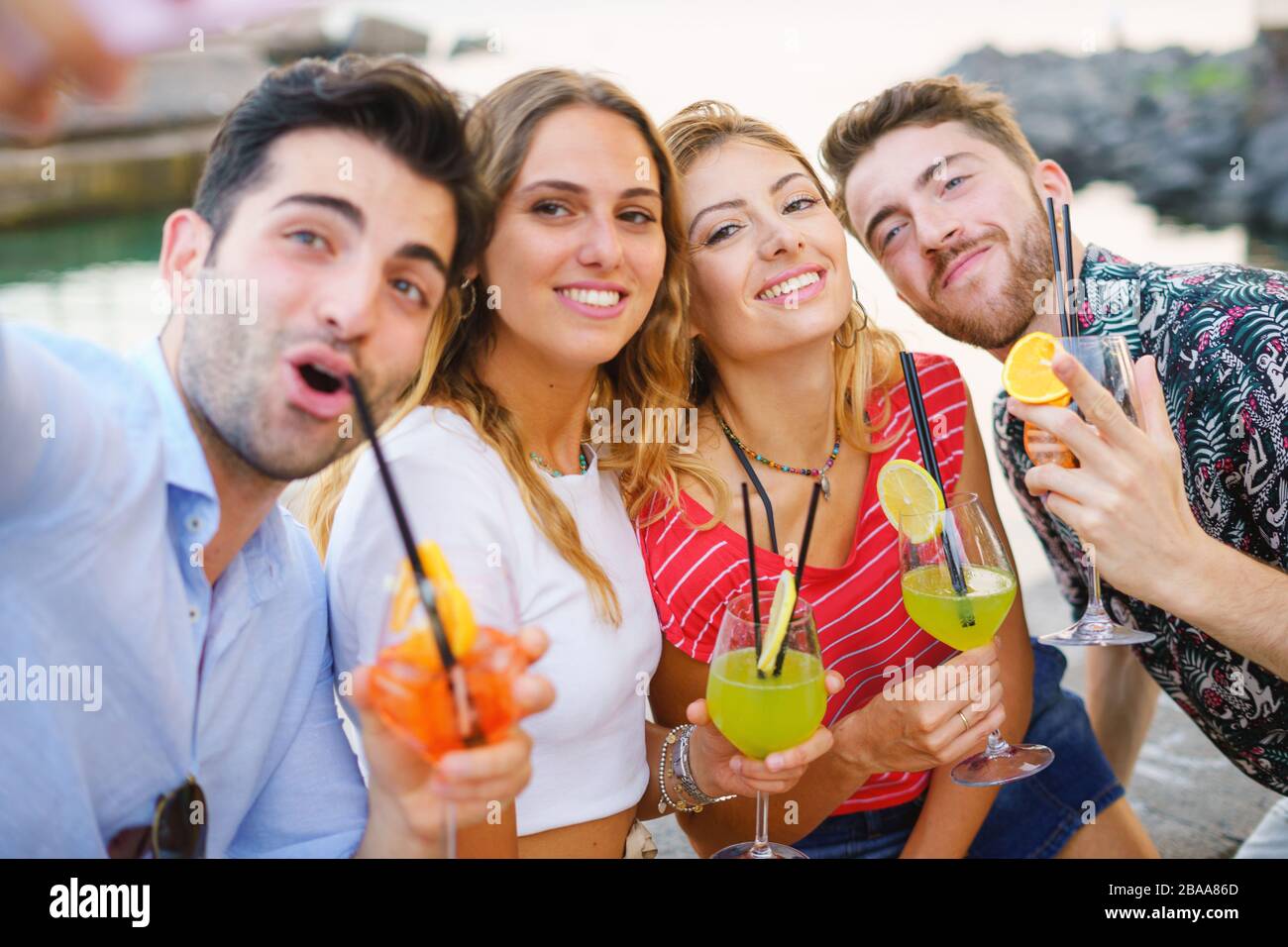 Gruppo di amici migliori divertirsi facendo selfie con lo smartphone e bevendo cocktail colorati al mare Foto Stock