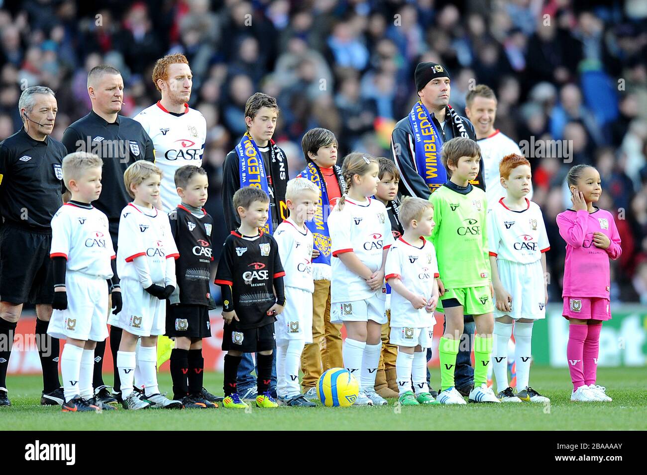 Milton Keynes Dons mascotte si allineano con i funzionari della partita prima del calcio d'inizio Foto Stock
