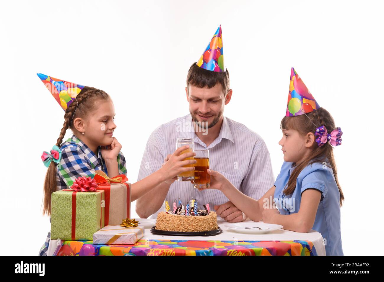 Bambini e papà banging gioiosamente bicchieri di succo durante una festa di compleanno Foto Stock