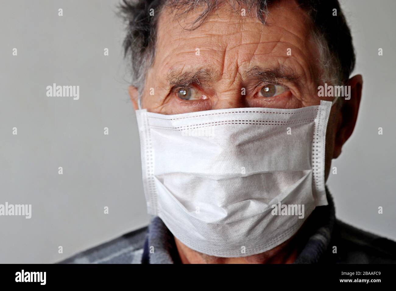 L'uomo anziano nella maschera medica sembra turbato. Concetto di protezione da coronavirus COVID-19, malattia, febbre, freddo e influenza Foto Stock