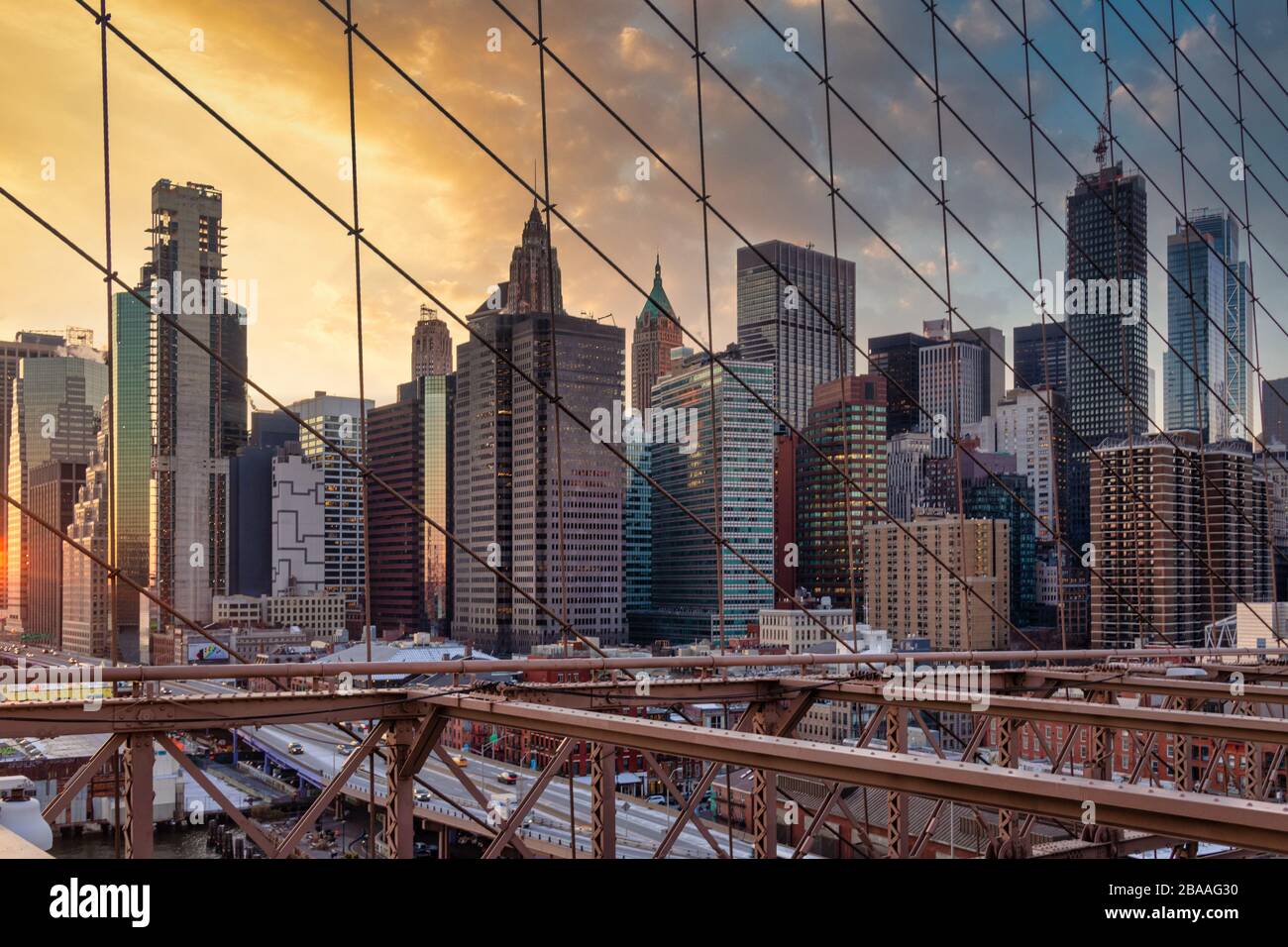 Skyline di New York dal ponte di Brooklyn al tramonto in inverno con nuvole nel cielo sullo sfondo Foto Stock