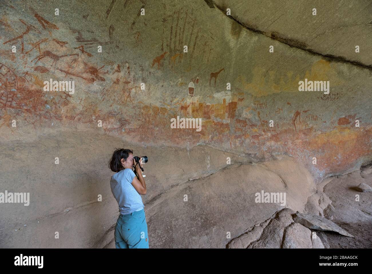 Un turista scatta una fotografia dell'arte di San Rock nella Grotta delle Inanke, il Parco Nazionale di Matobo, Zimbabwe. Foto Stock