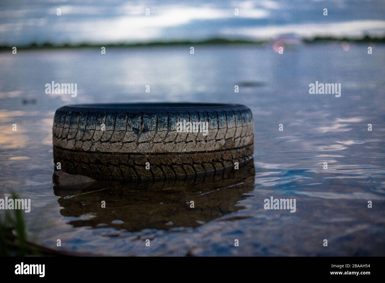 Un pneumatico di gomma per auto si trova nel lago Red, nella contea di Westmeath, l'isolamento come simbolo in Irlanda. Foto Stock