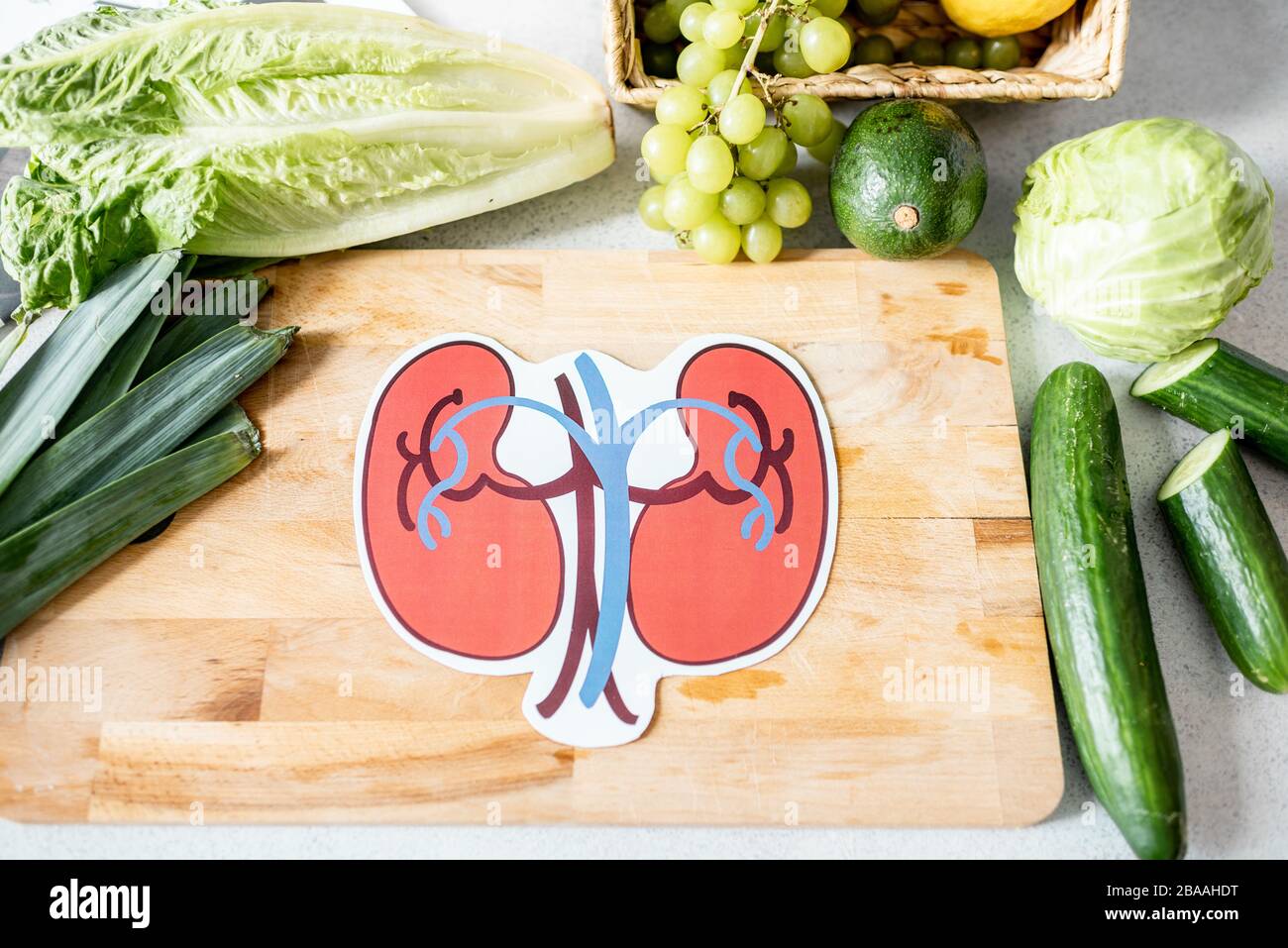 Reni umani disegnati sul tagliere con alimenti freschi verdi, vista dall'alto. Cibo per reni concetto di salute Foto Stock