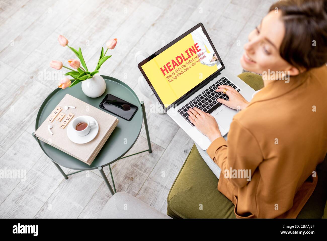 Donna che lavora con un po 'di web design sul computer mentre si siede su un comodo divano a casa, vista dall'alto. Concetto di lavoro da casa in un'atmosfera accogliente Foto Stock