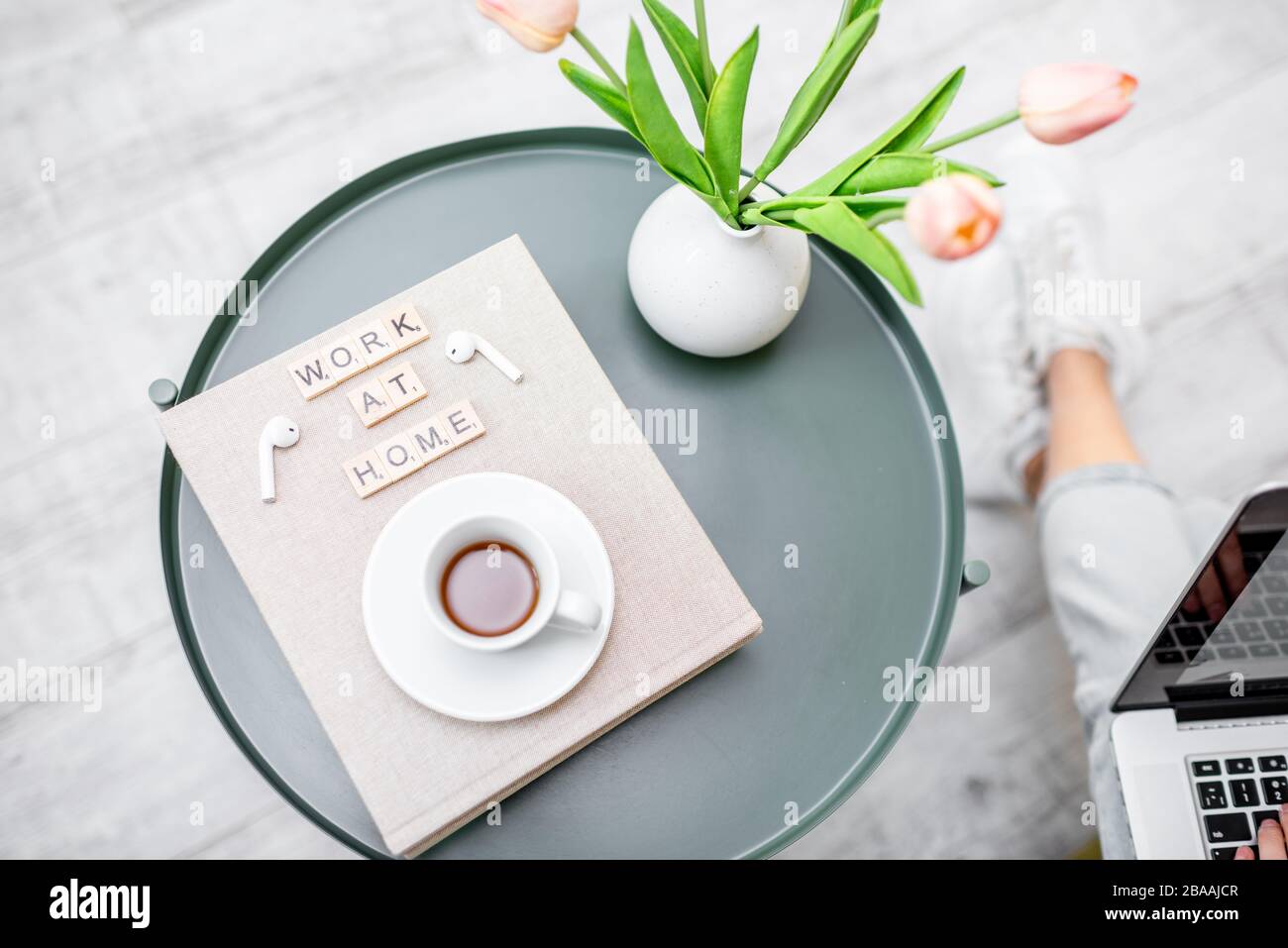 Fiori, libri e una tazza di caffè su un tavolo rotondo all'interno, vista dall'alto. Lavoro a casa e atmosfera accogliente casa concetto Foto Stock