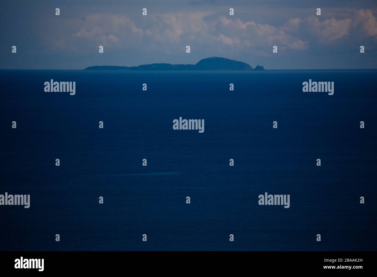 Un'isola scozzese vista dalla costa dell'Irlanda del Nord in un tranquillo cielo blu giorno. Foto Stock