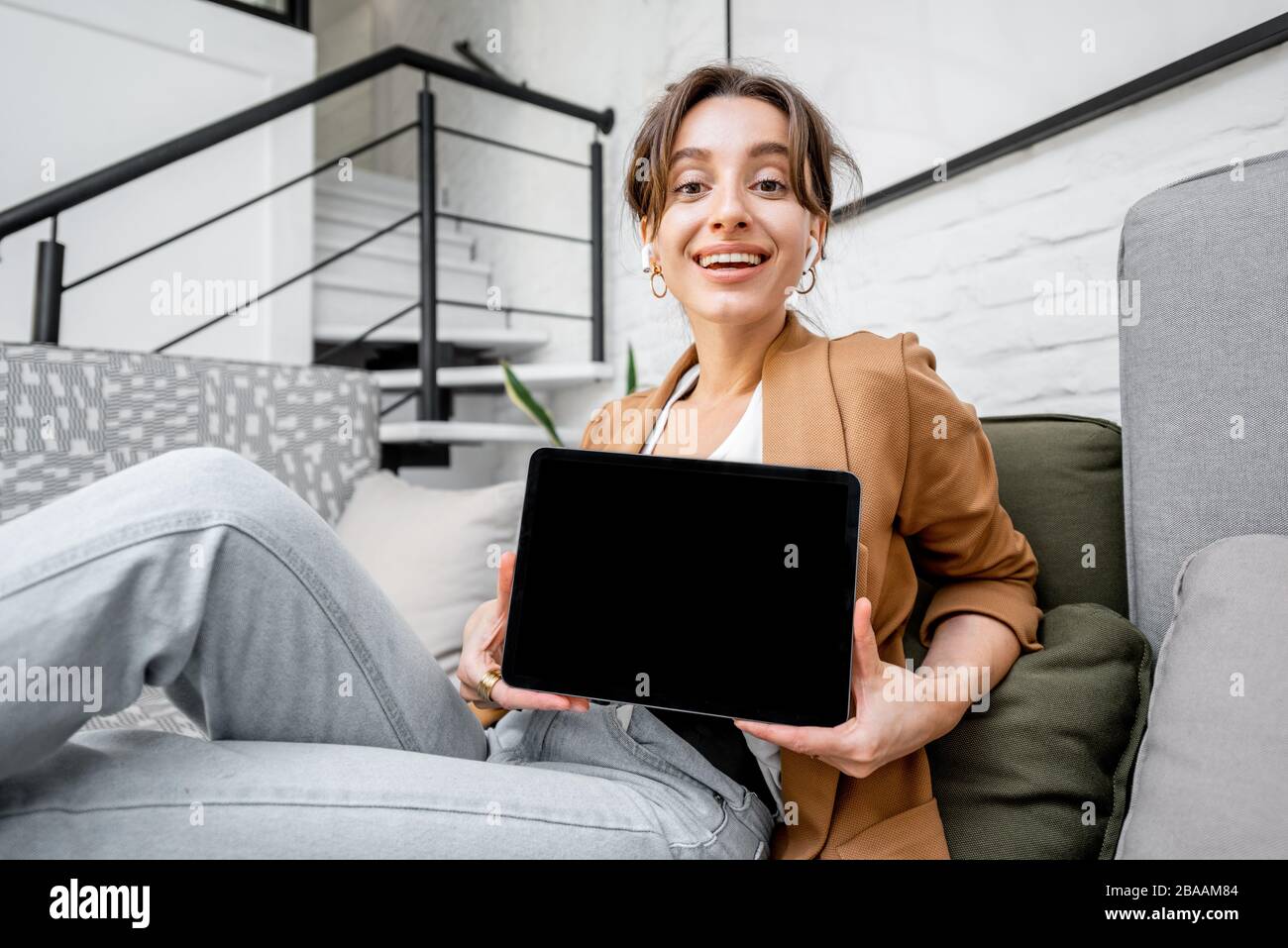 Donna giovane e allegra con un tablet digitale a casa. Tablet con schermo nero per copiare spazio Foto Stock