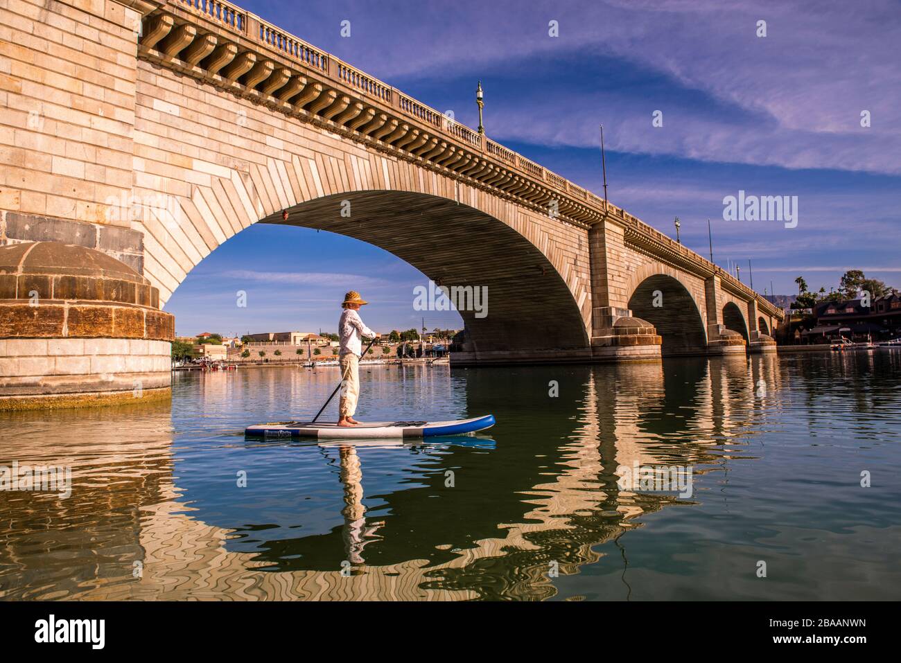 Paddle boarding donna sotto London Bridge, Lake Havasu, Havasu City, Arizona, Stati Uniti Foto Stock