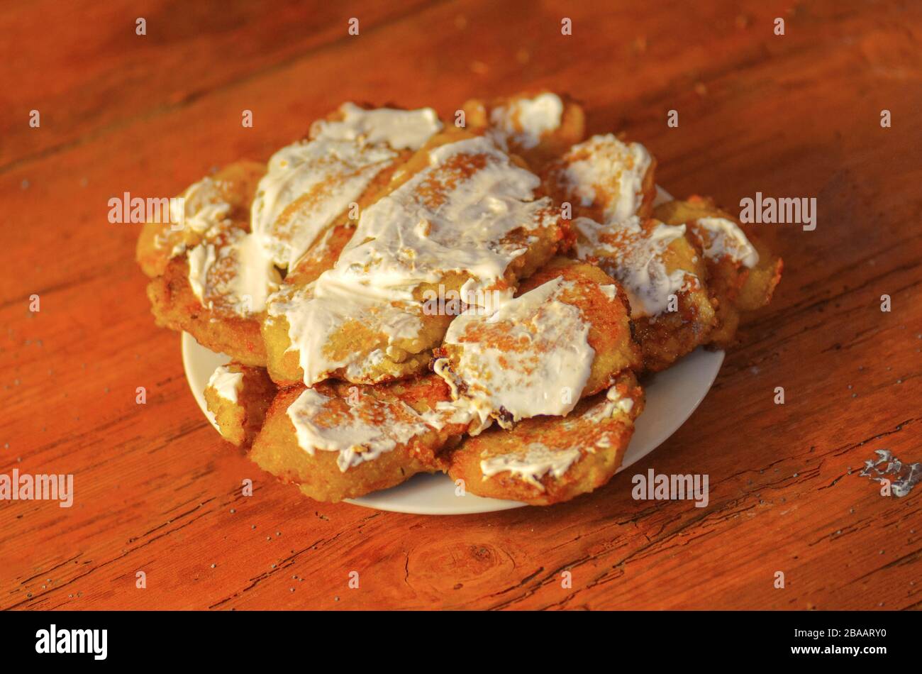 Piatto con gustose frittelle di patate su tavolo rustico in legno. Pancake o latkes di patate serviti con panna acida Foto Stock